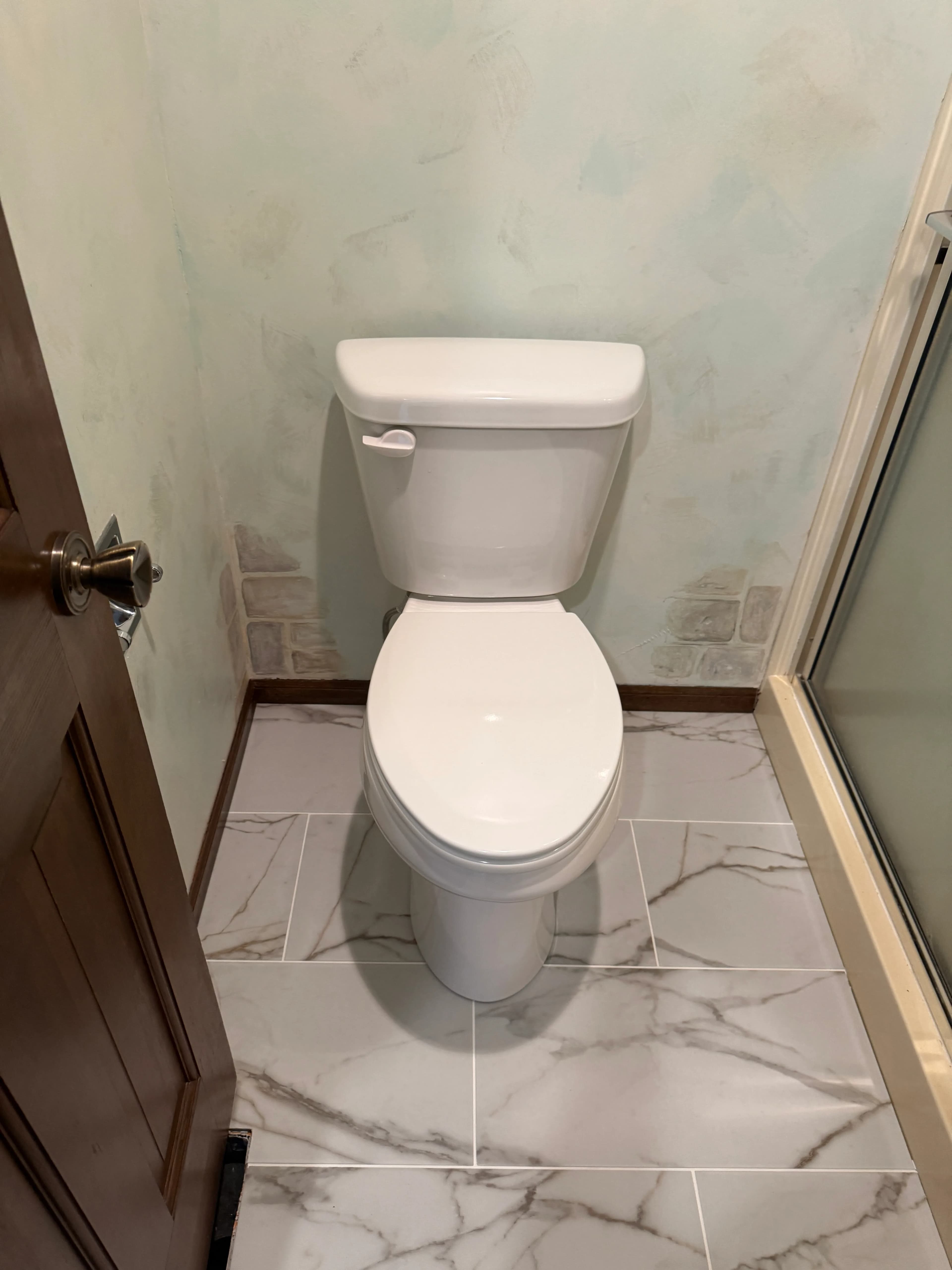 White toilet on marble-look tile in a residential bathroom