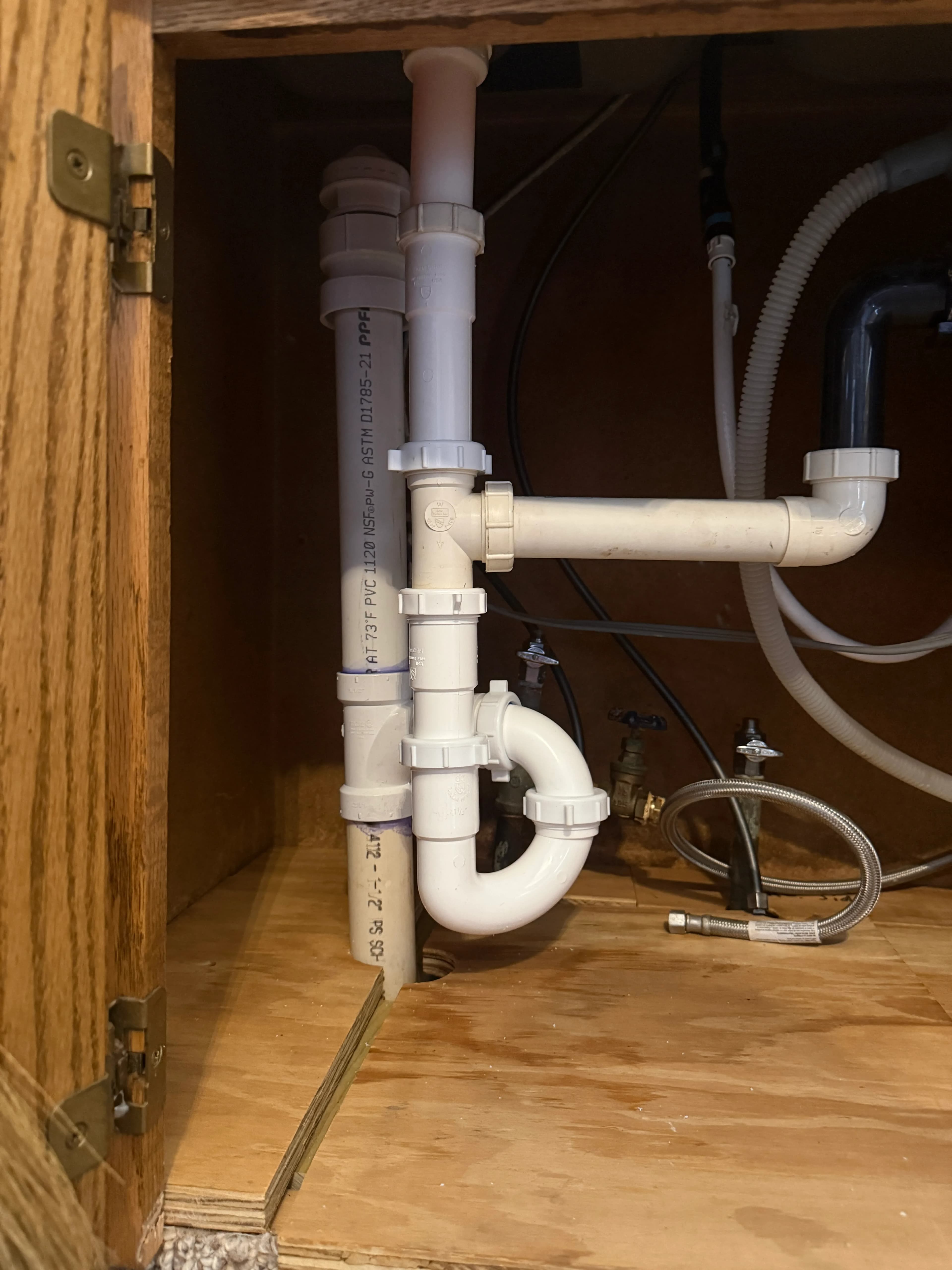 White PVC drain piping and Studor vent under a kitchen sink cabinet